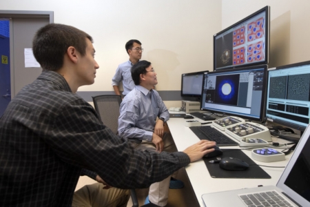 Christopher Addiego (left), a UCI graduate student in physics & astronomy; Xiaoqing Pan (seated in center), UCI’s Henry Samueli Endowed Chair in Engineering and a professor of both materials science & engineering and physics & astronomy; and Wenpei Gao (standing), a UCI postdoctoral researcher in materials science & engineering, were able to visualize the electric charge density of materials at sub-angstrom resolution using a new scanning transmission electron microscopy technique. Steve Zylius / UCI