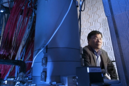 Xiaoqing Pan, UCI professor of materials science and engineering and physics, Henry Samueli Endowed Chair in Engineering, and director of the Irvine Materials Research Institute is seated next to IMRI’s Nion Ultra Scanning Transmission Electron Microscope. The instrument was used to make atomic-scale observations of phonon interactions in crystals, the subject of a new paper in Nature. Steven Zylius / UCI